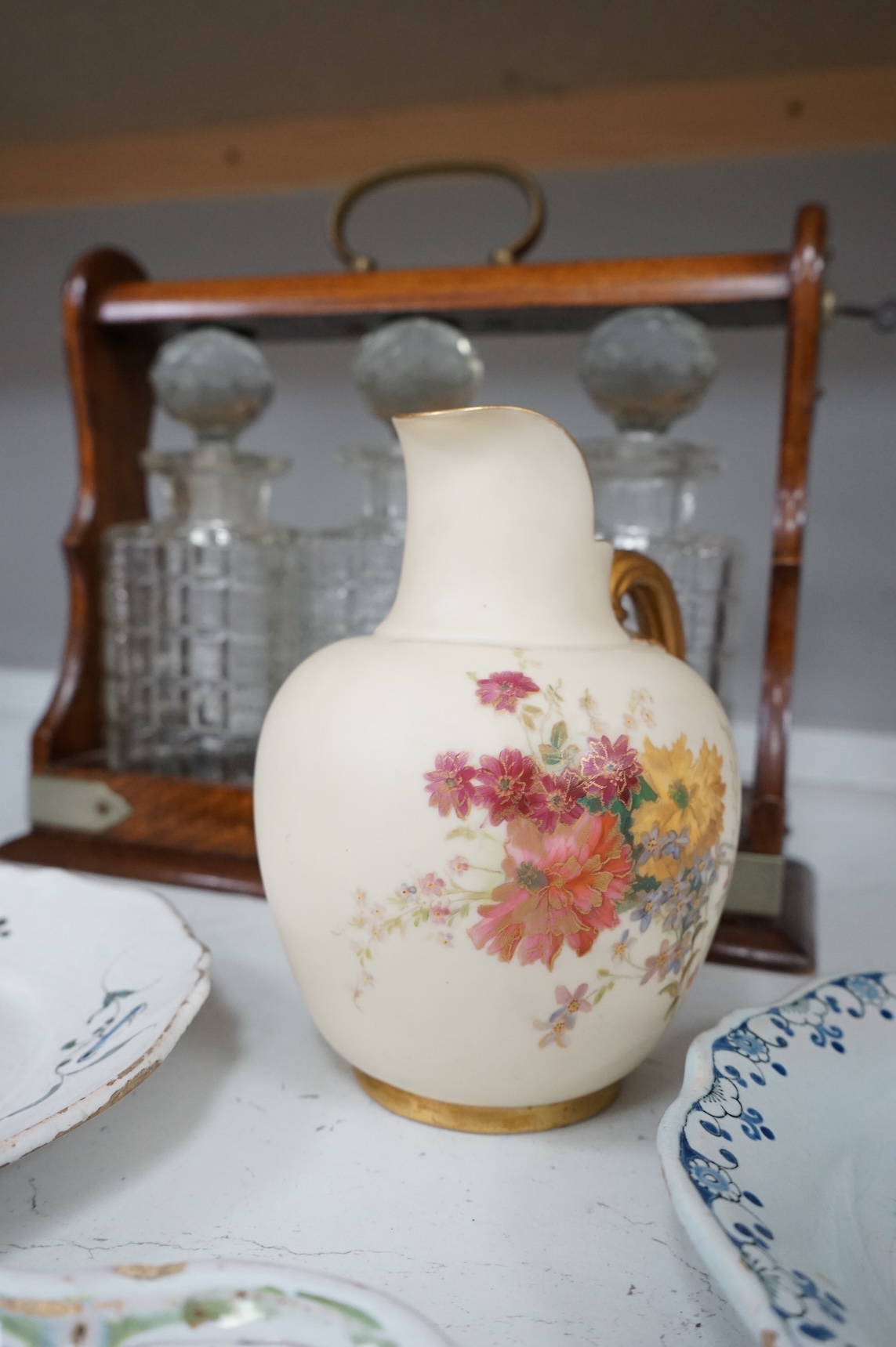 An oak three bottle tantalus, with key, together with three 18th/19th century faience plates and a Royal Worcester jug, tantalus 36cm wide